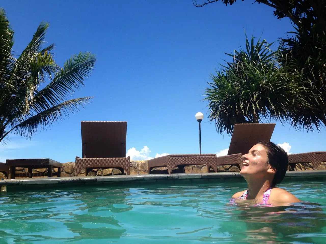 Woman relaxing in a swimming pool surrounded by tropical scenery near Balian Beach Bali