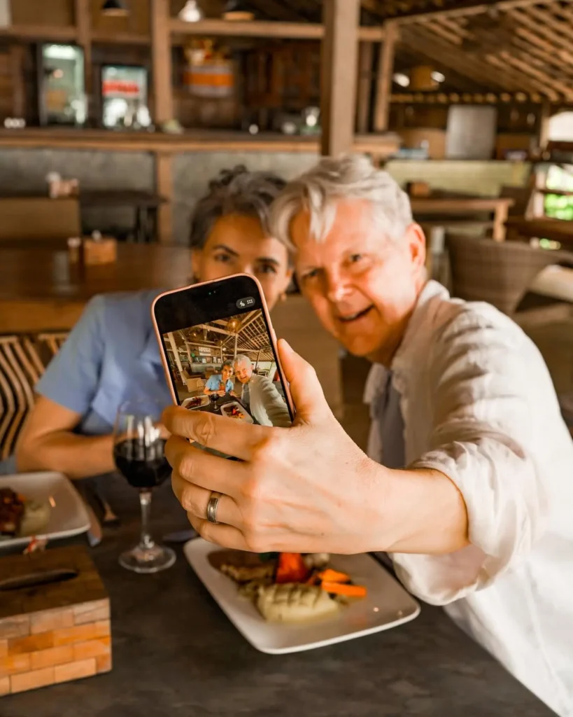Couple enjoying a relaxed meal and taking a selfie at a beachfront restaurant in Balian Beach Bali